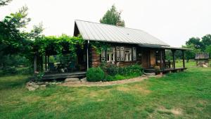 a small cabin with a porch on a grass field at Uroczysko Grabowiec in Grabowiec