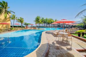 una piscina con mesas, sillas y sombrillas en Beach Park Resort - Oceani en Aquiraz