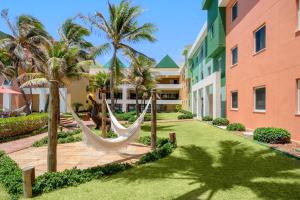 a resort with hammocks and palm trees next to a building at Beach Park Resort - Oceani in Aquiraz