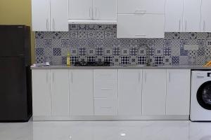 cocina con armarios blancos y nevera negra en Lavender, S.Feydhoo, Addu city, en Feydhoo