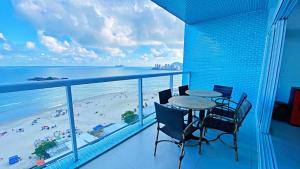 a balcony with a table and chairs and a beach at Apto cinematográfico vista mar in Guarujá