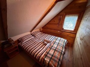 a bed in a attic with a plaid blanket at Uroczysko Grabowiec in Grabowiec