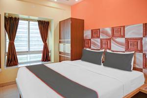 1 dormitorio con 1 cama blanca grande y pared de color naranja en Collection O New Avro Hotel Near Eco Park en Salua