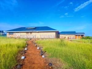 a field with rows of plants in front of a building at Resian Mara Camp in Talek