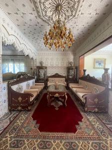 een woonkamer met een kroonluchter en een rood tapijt bij Villa avec piscine & proche mer - sans vis a vis 