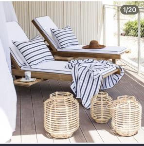 a rattan chair on a porch with two baskets at CasaNoa Luxury Villa Bed and Breakfast in Jávea