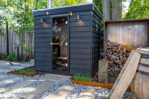 ein schwarzes winziges Haus in einem Hof mit einem Zaun in der Unterkunft 86, Bed & Outdoor Wellness - Sauna, Hottub, Icebath & Outdoor Shower included! in Oisterwijk