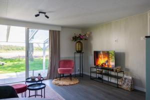 ein Wohnzimmer mit einem roten Sessel und einem Fernseher in der Unterkunft 86, Bed & Outdoor Wellness - Sauna, Hottub, Icebath & Outdoor Shower included! in Oisterwijk