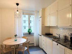a kitchen with a table and a table and a window at Stay Inn Söder Cozy apartment in Stockholm