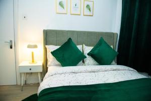 a bedroom with a bed with green pillows at Newly Refurbished - Affordable Four Bedroom Semi-Detached House Near Luton Airport and Luton Hospital in Luton