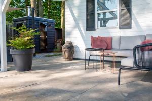 eine Terrasse mit einem Sofa, einem Tisch und Stühlen in der Unterkunft 86, Bed & Outdoor Wellness - Sauna, Hottub, Icebath & Outdoor Shower included! in Oisterwijk
