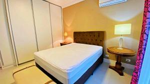 a bedroom with a bed and a table with a lamp at Apto cinematográfico vista mar in Guarujá