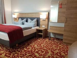 Landgasthof Hotel Hirsch في Marktlustenau: غرفة فندق بسرير مع سجادة حمراء
