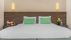 duże białe łóżko z 2 zielonymi poduszkami w obiekcie Domina Coral Bay Resort, Diving , Spa & Casino w Szarm el-Szejk