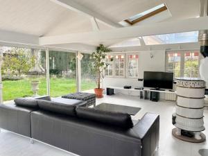ein Wohnzimmer mit einem schwarzen Sofa und einem TV in der Unterkunft VERANDA, maison pour 8 personnes in Mulhouse