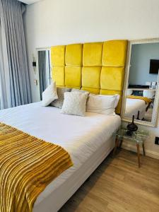 1 dormitorio con 1 cama grande y cabecero amarillo en Sandton Serenity: UltimateGetaway 2, en Johannesburgo