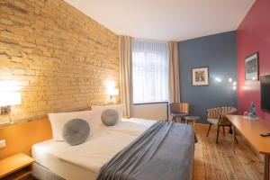 a bedroom with a bed and a brick wall at Boutique Hotel Schwarzer Baer in Lutherstadt Wittenberg