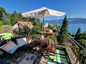 a table and chairs on a balcony with an umbrella at Apartment camelie with private beach in Baveno