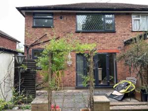 a brick house with a back yard with plants at Stunning 3-Bed House in Cheadle in Cheadle
