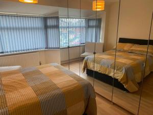 契德爾的住宿－Stunning 3-Bed House in Cheadle，一间卧室设有两张床、一把椅子和窗户。