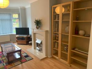 a living room with a tv and a book shelf at Stunning 3-Bed House in Cheadle in Cheadle