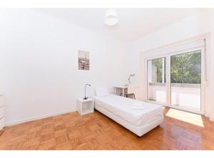 a white bedroom with a bed and a window at HOUZE_Central Lisbon 4 room flat in Lisbon