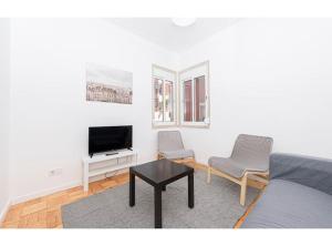 a living room with a bed and two chairs and a television at HOUZE_Central Lisbon 4 room flat in Lisbon