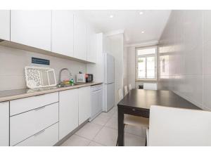 a white kitchen with a table and a microwave at HOUZE_Central Lisbon 4 room flat in Lisbon