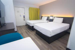 a hotel room with two beds and a chair at Studio 6 Extended Stay - West Palm Beach, FL in West Palm Beach