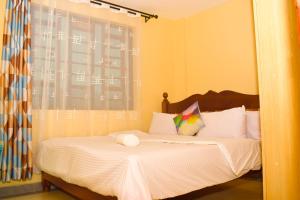 a bedroom with a bed with white sheets and a window at Lighthomes Two Bedroom Thika CBD in Thika