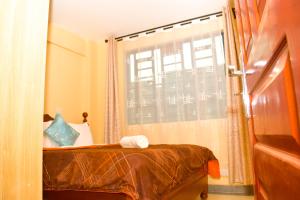 a small bedroom with a bed and a window at Lighthomes Two Bedroom Thika CBD in Thika