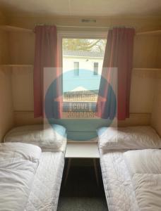 two beds in a small room with a window at 3 Bedroom Caravan for Hire Butlins Minehead in Minehead