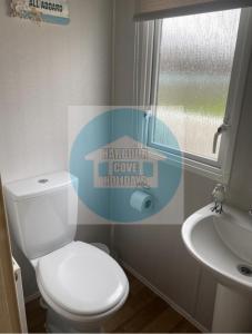 a bathroom with a toilet and a sink and a window at 3 Bedroom Caravan for Hire Butlins Minehead in Minehead