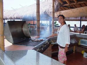 a woman is cooking food on a grill at Cruise Ship Southern Star At Dock Only in Bahía de Caráquez