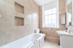 a white bathroom with a tub and a sink at Spacious & Central 3-bed flat by popular Waterloo! in London