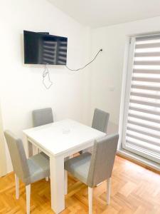 a white table with chairs and a tv on a wall at Silver Apartment with private garage in Bar