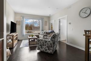 a living room with a couch and a clock on the wall at Sweet Tart Spot - Cozy TC Condo - Pet Friendly in Traverse City