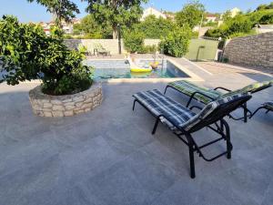 a bench sitting in front of a swimming pool at Luxury apartman Ani Sutivan Brač s bazenom i jacuzzijem in Sutivan