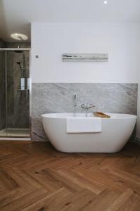 a bathroom with a white tub on a wooden floor at Woodhaven Stays in Scredington
