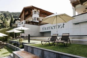 um grupo de cadeiras e um guarda-sol em frente a um edifício em Hotel Thurnerhof em Saalbach-Hinterglemm