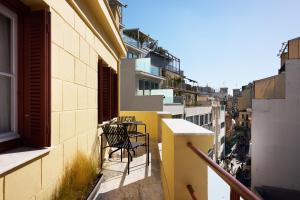 a balcony with a table and chairs on a building at Vrachos Athens Suites in Athens