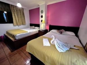 2 camas en una habitación de hotel con paredes rosas en La Rosario, en Quito