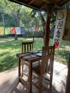 uma mesa de madeira com 2 cadeiras e uma mesa com copos de vinho em OM SHAMBALA Yoga Ashram em Anuradhapura
