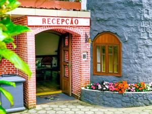 una fachada de un restaurante con una puerta y flores en VELINN Áustria Hotel Monte Verde, en Monte Verde