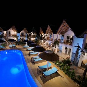 a pool at night with umbrellas and lounge chairs at Olzadia Boutique Hotel in Michamvi