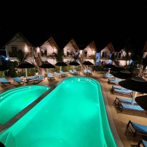 a swimming pool at night with chairs and umbrellas at Olzadia Boutique Hotel in Michamvi