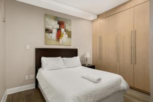 a bedroom with a white bed and wooden cabinets at Hydro Park Residences in Sandton WITH GENERATOR in Johannesburg