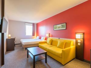 ein Wohnzimmer mit einem gelben Sofa und einem Bett in der Unterkunft B&B HOTEL Compiègne Thourotte in Thourotte