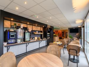 a restaurant with tables and chairs and a bar at B&B HOTEL Compiègne Thourotte in Thourotte