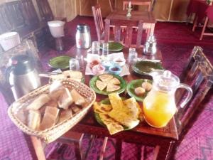 a table topped with plates of food and orange juice at berber sahara in Zagora